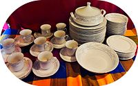 Complete set showing cups with saucers, large plates, bowls, and soup tureen with lid, all with Somerset pattern and double silver trim on white ceramic.