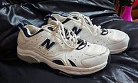 Side view of the pair of white and navy New Balance running shoes showing brand logos and overall condition