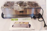 Front view of stainless steel buffet server with three buffet pans covered in plastic wrap and power cable, instruction manual included in front.