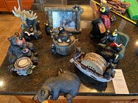 Overview of bear figurine collection showing various bears with different poses and accessories including candle votive, reading bear, bear in boat