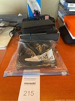 Photo showing black zippered case likely containing HP external DVD player, a corded phone partially visible, and a plastic bag with an accessory or manual.