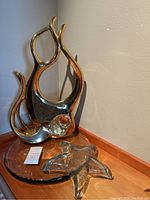 Gold ceramic abstract fish sculpture sitting on clear glass platter, with clear glass starfish nearby, showing full lot arrangement