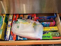 Drawer with assorted storage bags, foil, plastic wrap, vegetable bags, and wax paper visible.