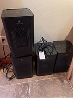 Four black Medify Air Purifiers side-by-side and stacked, showing front perforated panels and power cords.