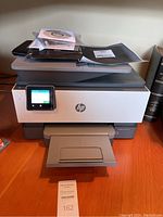 Front view of the printer showing installed touchscreen, paper tray, and included installation CDs and manuals on top.