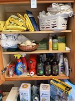 Wide view of the wooden shelving with folded towels, cleaning products, microfiber cloths, sponge, and a laundry basket
