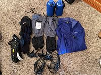 Wide view showing full lot including Threshold leg gaiters, Patagonia jacket, gloves, water bottles, ice grippers, and ski pole tips.