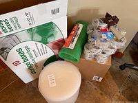 Overall view of packing materials including storage box, bubble wraps, tape rolls, and tape dispenser