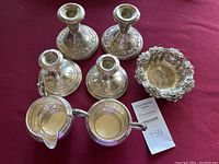Top view of candle holders, creamer, sugar bowl, and decorative dish laid on a red cloth.