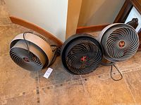 Three Vornado fans positioned on tile floor, cords visible.