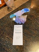 Full view of carved gemstone toucan mounted on amethyst base on countertop.