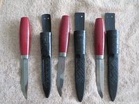 Set of three Mora Classic Wood Handle knives with blades exposed and plastic sheaths beside them
