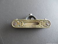 Top view of the antique pocket spirit level showing the brass plate with embossed decorative pattern and transparent vial window with bubble.