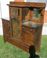Front and side view of antique wooden buffet sideboard with glass display cabinet and mirrored sides, showing the faux wood grain finish and hardware.
