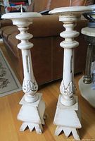 Pair of white painted antique carved wooden candle stands showing general wear and paint chipping.