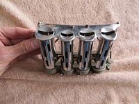 Front view of the four cylindrical metal barrels with slots for coins, showing polished condition and structural details.