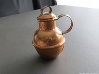 Front and side view of copper milk jug showing bulbous base, lid and handle