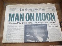 Front page of newspaper with headline 'MAN ON MOON' and photo of lunar landing, clear text and imagery.