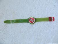 Front view of the Coca-Cola Swatch watch showing green translucent strap and red face with Coca Cola imagery.