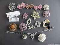Full overview of all assortment brooches, earrings, necklace, and bracelet on a black background