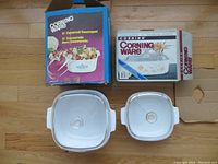 Two CorningWare covered saucepots with original boxes showing front and top views