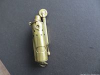Top-side view of the brass petrol trench lighter showing the perforated outer casing and the hinged cap.
