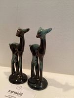 Pair of standing deer figurines photographed from front angle showing green and black glazing.