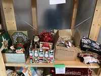 Photo of box and shelves containing various Christmas decorations including ceramic cardinals, Santa figurines, and fabric napkins.