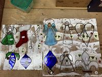 Two panels each showing five stained glass Christmas ornaments in various shapes and colors including angels, stockings, and teardrops