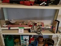 Full view of curling broom with gloves and croquet game in carrying case on shelf