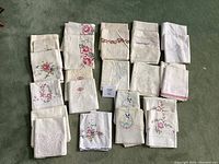 Top view of multiple folded pillowcases arranged on carpet showcasing different embroidery styles including colorful floral designs and lace details.