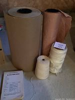 Two large rolls of brown butcher paper and two spools of thick twine on floor with paper and twine label.