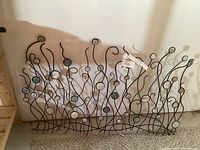 Wide shot of metal wall art showing full width and height, wall art leans against a white wall on the floor.