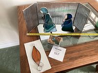 Overall view of nativity figures, leaf-shaped stained glass piece, reflective folding screen on wooden table