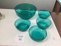 Photo showing one large turquoise glass salad bowl and four smaller matching bowls on a white surface with a MaxSold lot card.