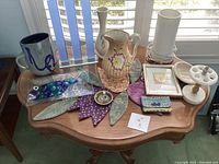 Overview of various pottery, lamp, trays, fabric pieces and decor items on wooden table