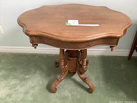 Top down perspective showing the scalloped oval solid wood tabletop with smooth finish and a small note on top.