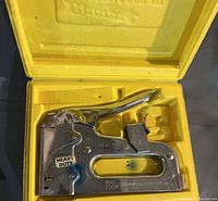 Chrome heavy duty Arrow T50 staple gun inside a yellow molded plastic case, showing the model number and 'Heavy Duty' label on the side.