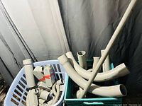 PVC conduit pipes and various fittings in a green crate including straight and curved sections.