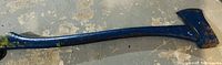 Photo of an axe with blue painted wooden handle and metal axe head showing wear.