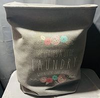 Gray canvas laundry bag with floral print and inspirational quote, showing the outside and liner fabric at top