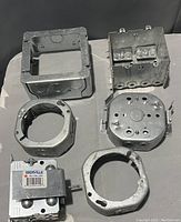 Top view of five metal electrical insert boxes laid out in a grid on a flat surface