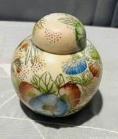 Front view of round ceramic ginger jar with lid, showing colorful floral painted pattern