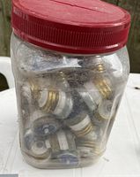 Two clear plastic jars with red lids filled with assorted threaded ceramic electrical fuses.