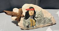 Front view of the ceramic pottery decor item featuring a Native American figure and wolves in relief on a beige base with a wooden cross element.