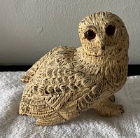 Front and side view of carved owl figurine showing detailed feather carvings and dark eyes.