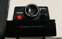 Close up front view of Polaroid Pronto! Land Camera showing lens, red shutter button and viewfinder