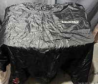 Black Aurora rain jacket spread out flat showing the front with logo on chest