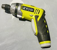 Ryobi cordless drill lying on a gray surface with visible adjustable torque settings and no battery attached.