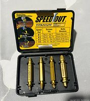 Open black plastic case showing four gold titanium drill bits sized for specific screw and bolt sizes, arranged in molded slots.